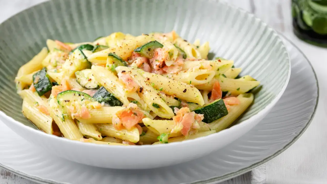 Penne con salmone e zucchine, un piatto cremoso e saporito, condito con erbe fresche e pepe nero.