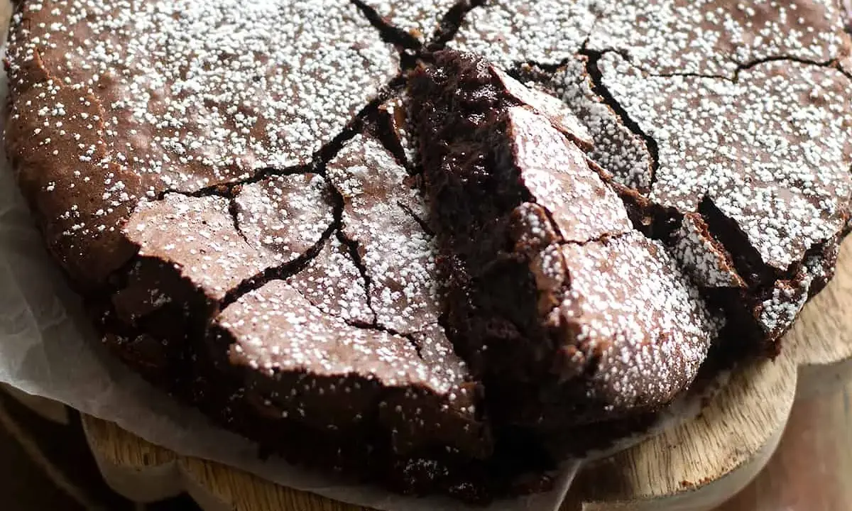 Una deliziosa torta al cioccolato fondente, con una crosta crepata e cosparsa di zucchero a velo, pronta per essere gustata.