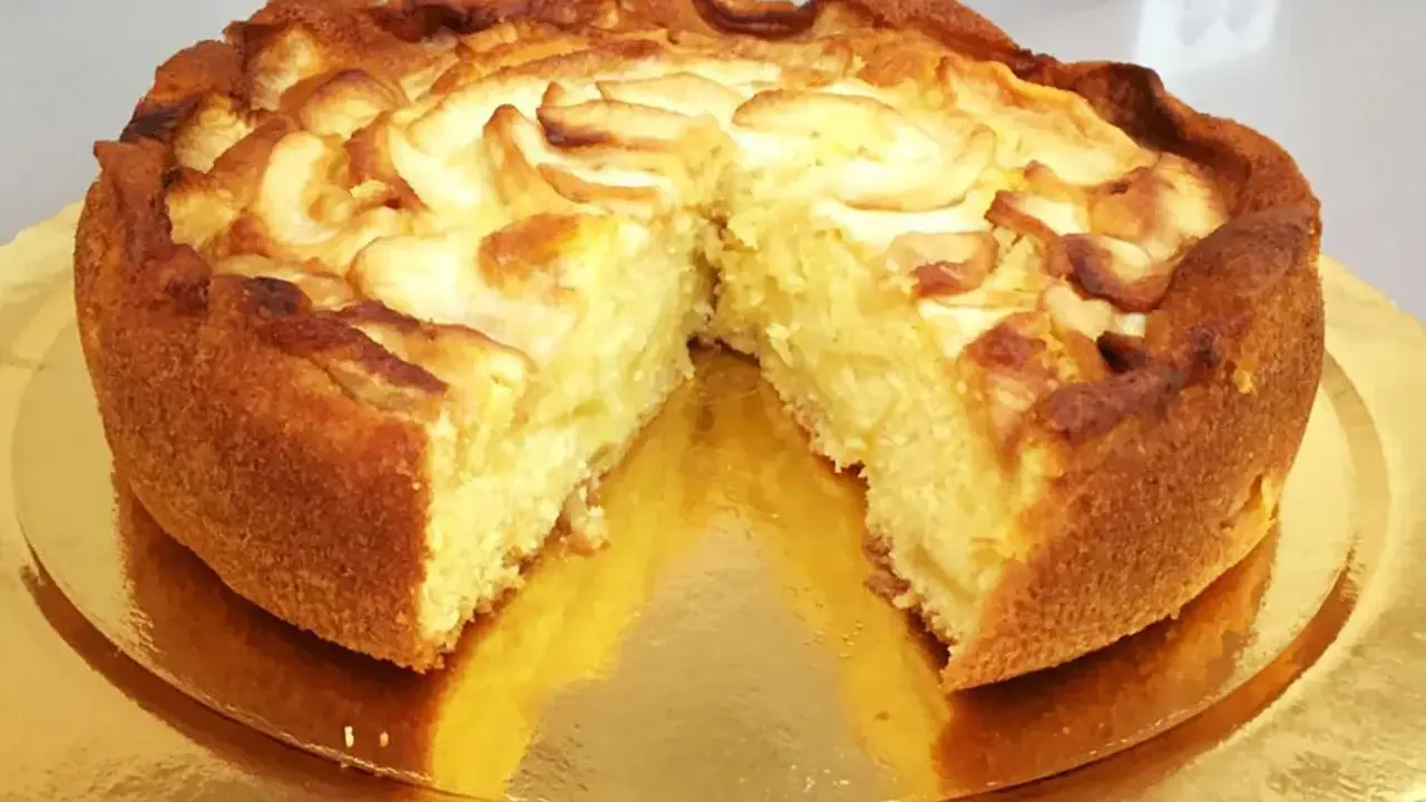 Una deliziosa torta di mele, dorata e soffice, con fette di mela disposte a spirale sulla superficie.