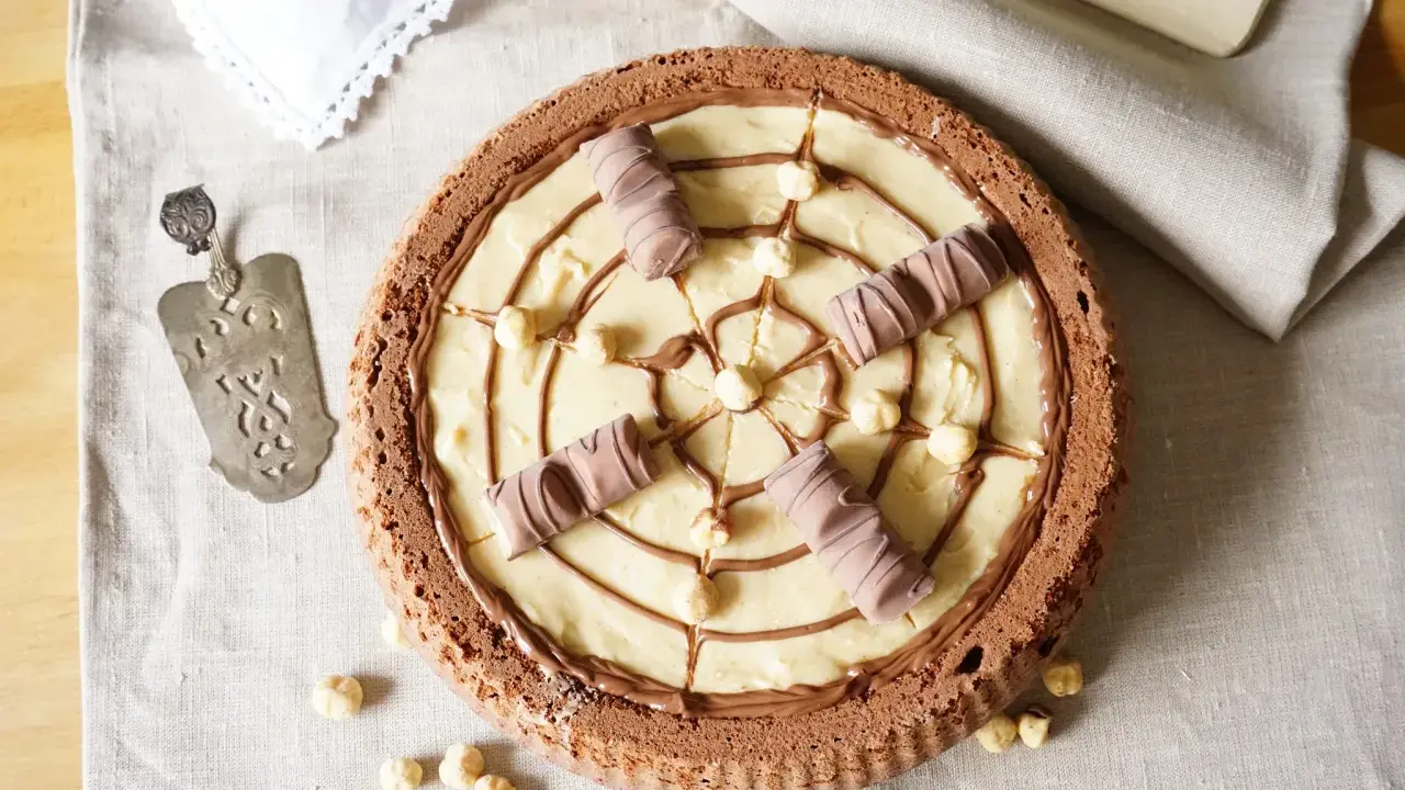 Torta Kinder Bueno con crema chiara, nocciole e decorazioni di cioccolato.