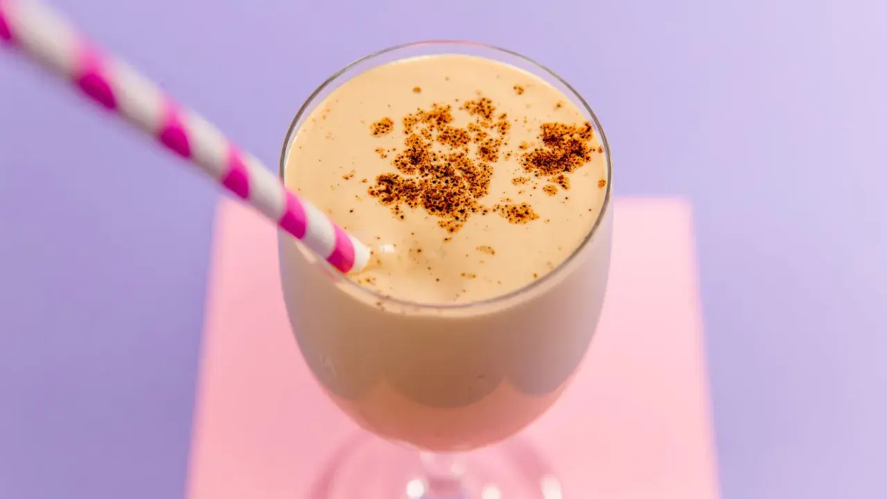 Delizioso spumone al caffè, guarnito con cacao in polvere, pronto da gustare con una cannuccia a righe rosa e bianche.