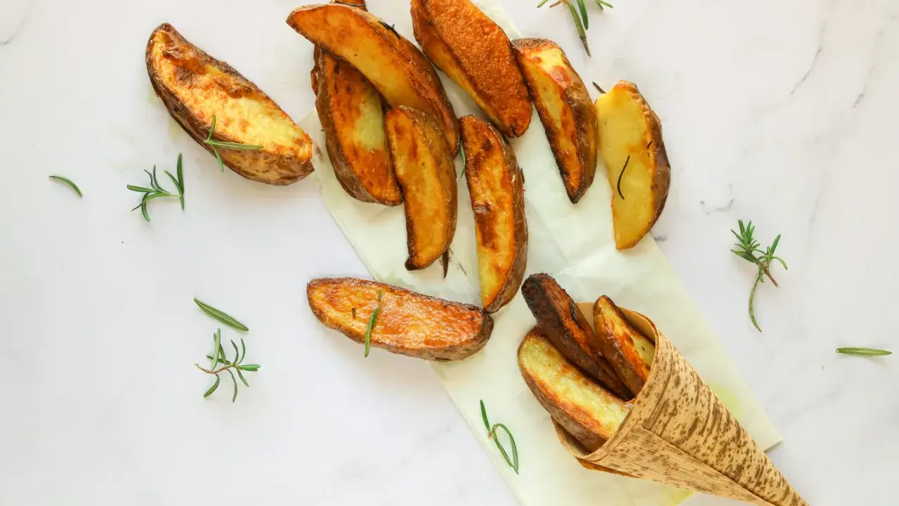 Patate al forno dorate e croccanti, guarnite con rametti di rosmarino fresco. Un piacere per gli occhi e per il palato.