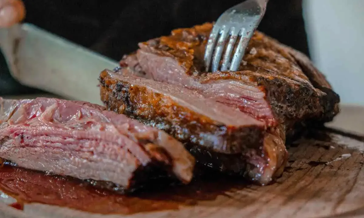 Un succulento arrosto di maiale, tagliato a fette su un tagliere di legno, con una forchetta che affonda nella carne tenera.