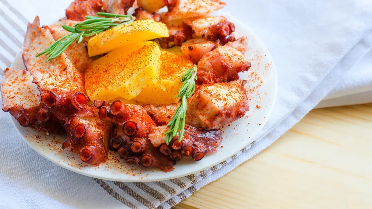 Un invitante polpo alla gallega, cosparso di paprika e guarnito con rosmarino e patate, pronto per essere gustato.