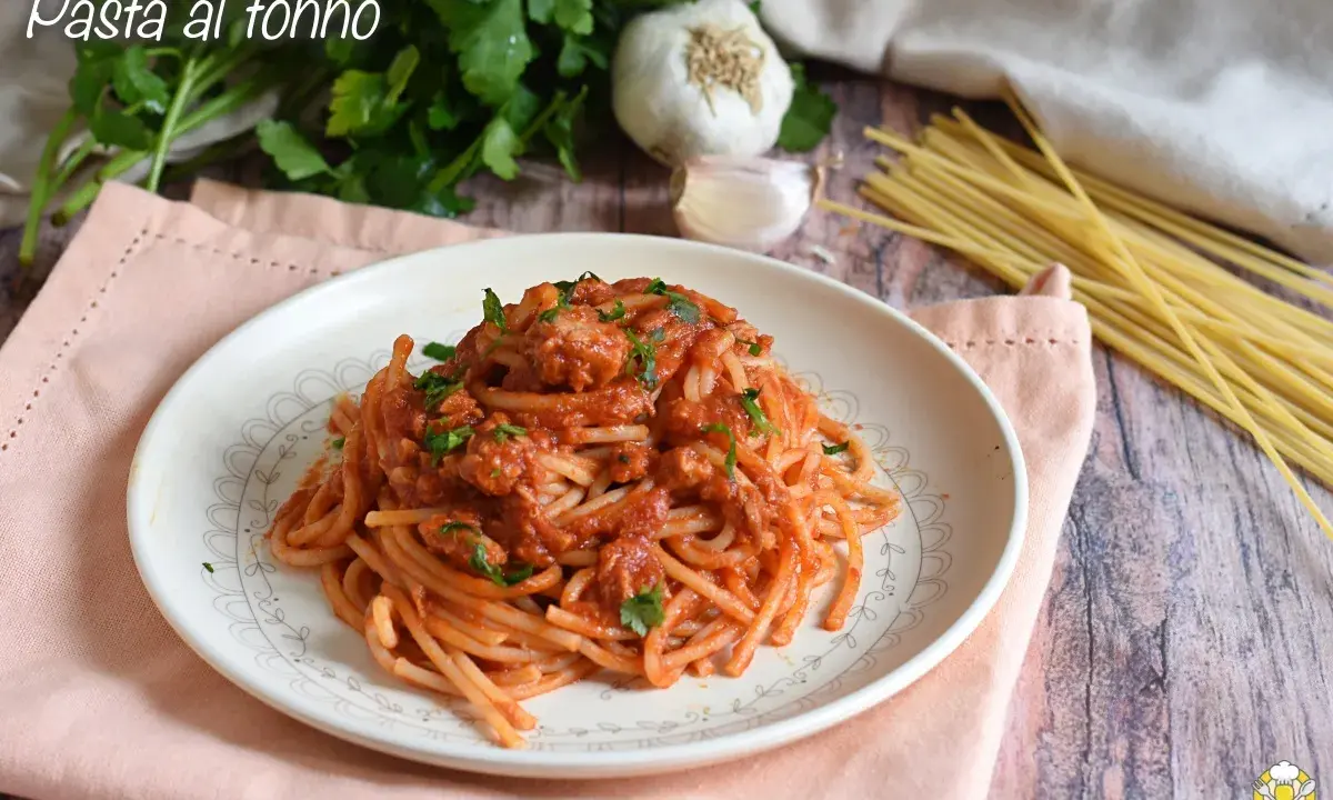 Piatto di spaghetti al sugo con tonno in scatola, guarnito con prezzemolo fresco. Ingredienti per un pasto veloce e gustoso.