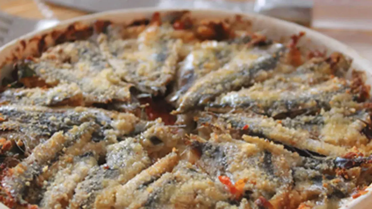 Tortino di alici cotto al forno, con panatura dorata e ingredienti saporiti.