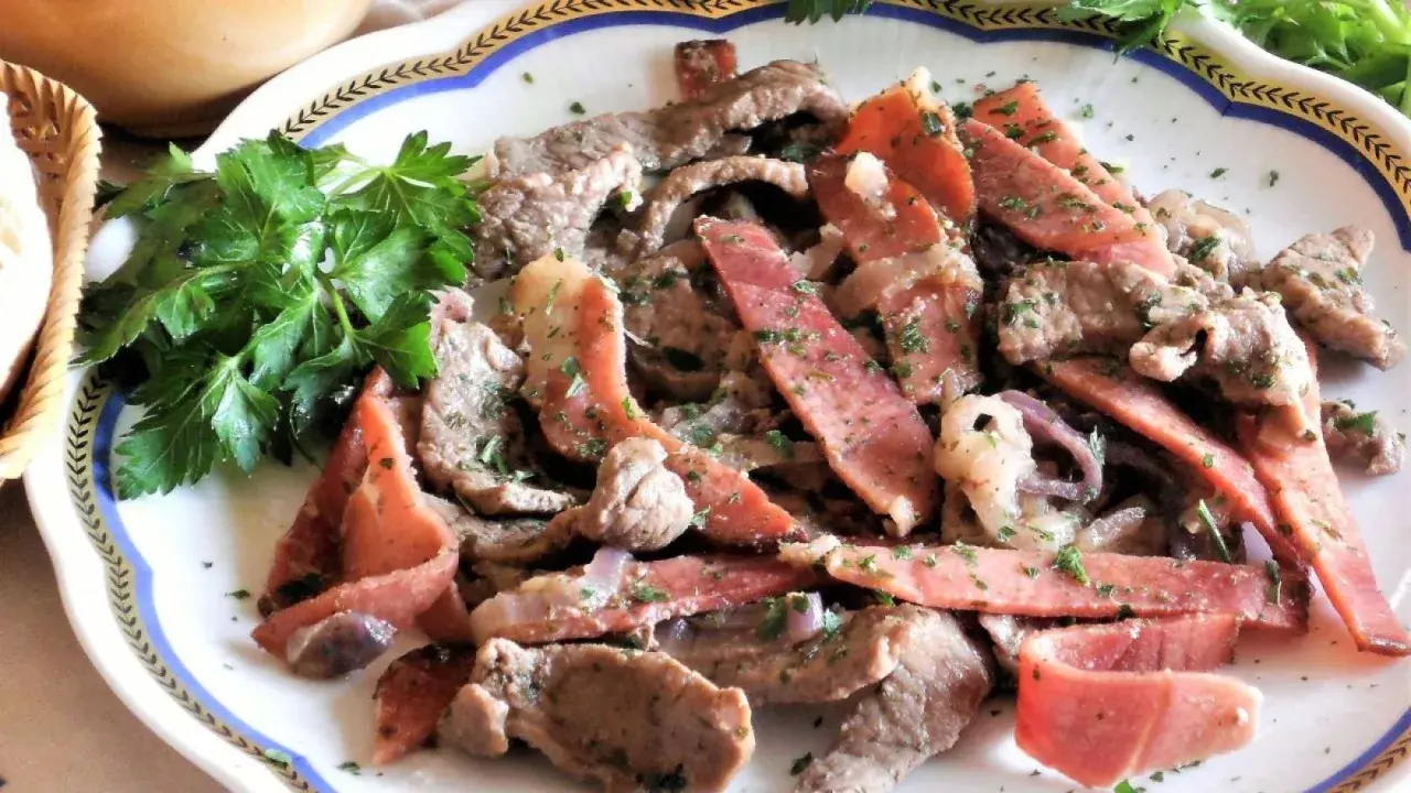 Straccetti di manzo con pancetta e cipolla, guarniti con prezzemolo fresco. Un piatto saporito e invitante.