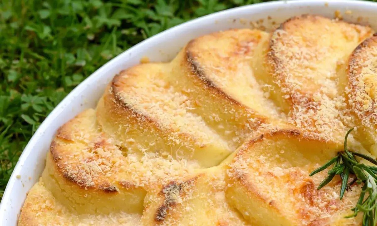 Gnocchi alla romana dorati e gratinati in una teglia bianca, con un rametto di rosmarino.