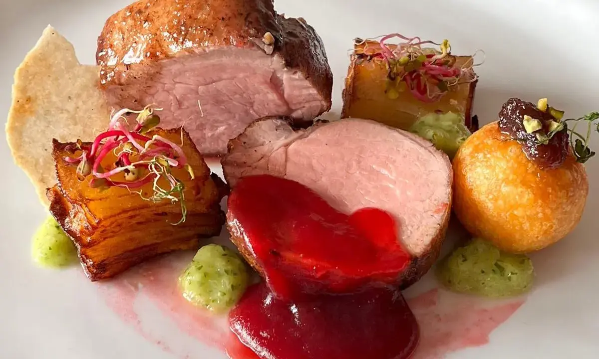 Piatto gourmet con filetto di maiale, patate croccanti, salsa rossa e guarnizioni verdi. Un'idea per le tue ricette di filetto di maiale.