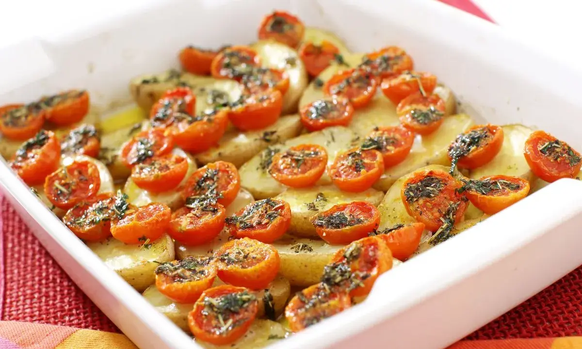 Pomodori gratinati al forno con patate, un piatto semplice e gustoso, pronto per essere infornato.