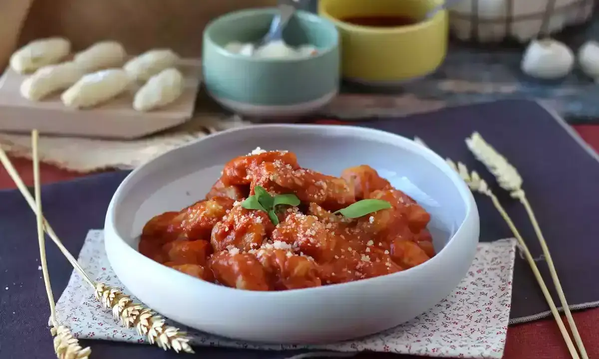 Un invitante piatto di gnocchi alla sorrentina, conditi con sugo rosso e parmigiano, guarniti con basilico fresco.