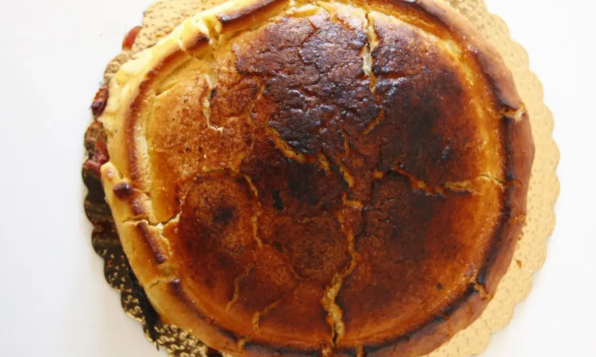 Crostata ricotta e visciole dorata e leggermente bruciacchiata, con un ripieno invitante che traspare dai bordi.