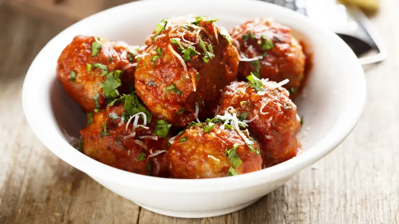 Polpette di carne morbide in salsa rossa, cosparse di parmigiano e prezzemolo fresco.