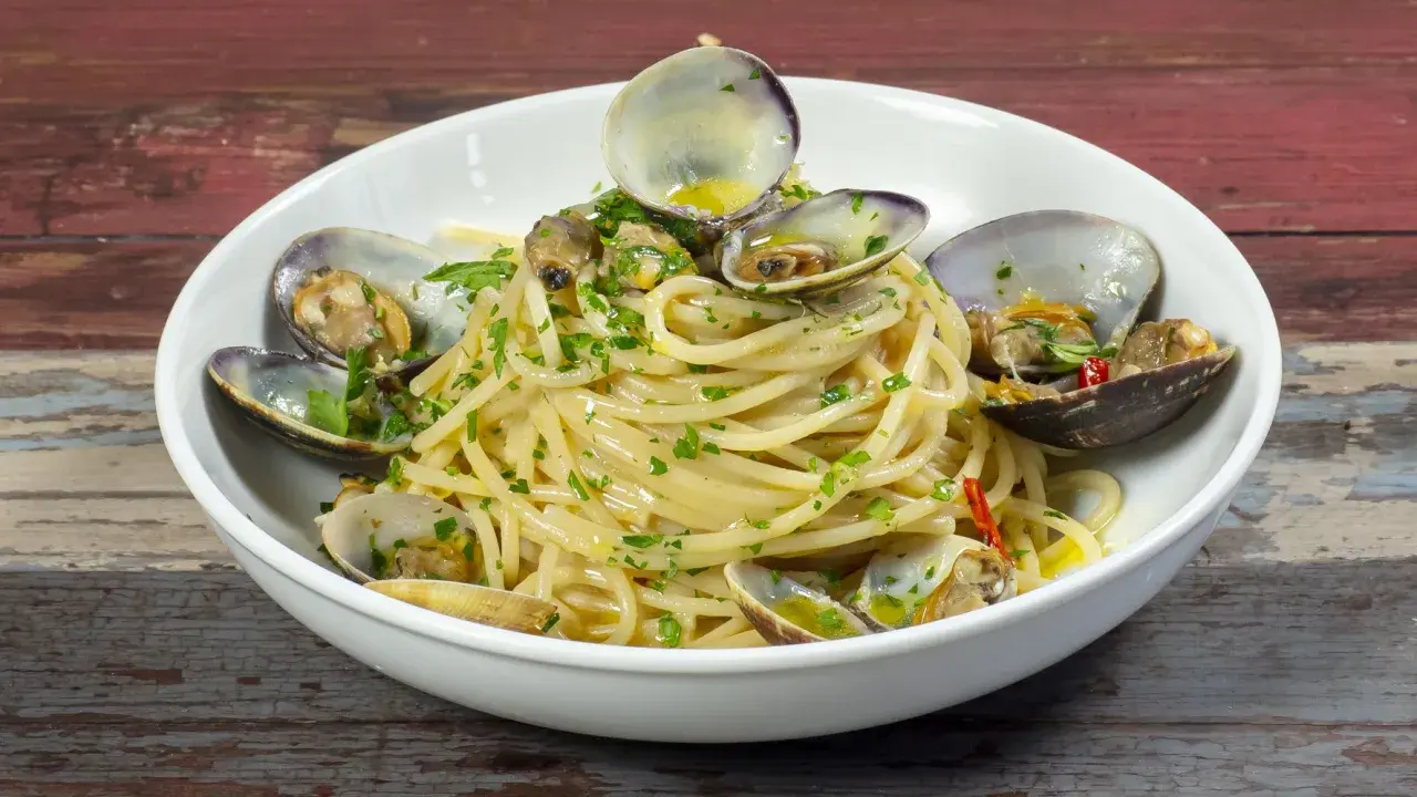 Spaghetti alle vongole surgelate, un piatto gustoso con pasta, vongole e prezzemolo.