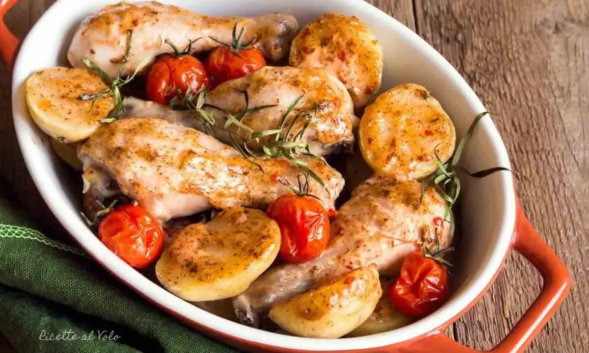 Delizioso pollo al forno con patate e pomodorini, guarnito con rosmarino fresco. Un piatto invitante e saporito.