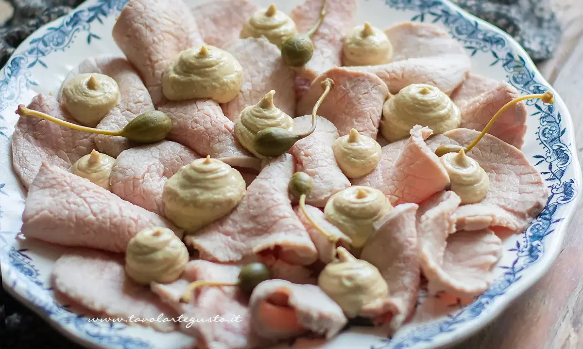 Vitello tonnato ricetta originale piemontese: fettine sottili di carne rosa, guarnite con salsa tonnata e capperi.