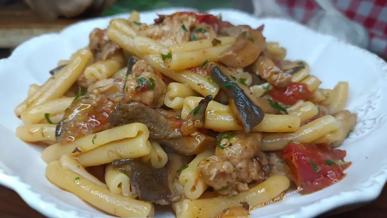 Un piatto invitante di pasta funghi e salsiccia, condita con pomodoro e prezzemolo, pronta per essere gustata.