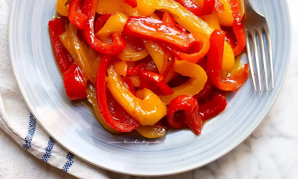 Piatto di peperoni in agrodolce, rossi e gialli, succosi e lucidi, pronti per essere gustati.