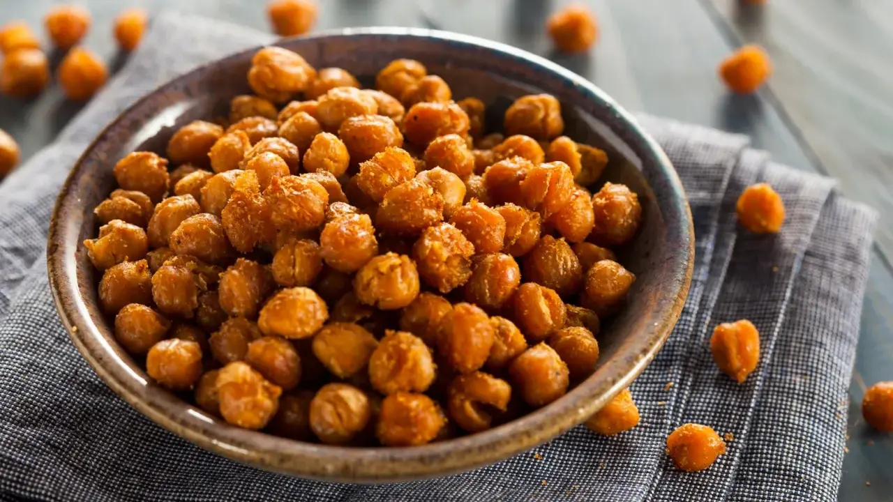 Ceci croccanti al forno, uno snack salutare e gustoso, serviti in una ciotola su un tovagliolo di lino.