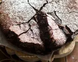 Una deliziosa torta al cioccolato fondente, con una crosta crepata e cosparsa di zucchero a velo, pronta per essere gustata.