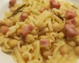 Piatto di pasta e ceci in scatola, con cubetti di pancetta e un rametto di rosmarino.