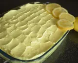 Un invitante tiramisù al limone, guarnito con fette di limone fresco e limoni interi, pronto per essere gustato.