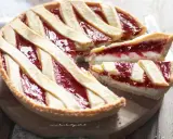 Una deliziosa crostata ricotta e marmellata, con fette tagliate che mostrano il ripieno cremoso e la crosta dorata.
