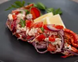 Astice alla catalana: un piatto fresco con astice, pomodoro, cipolla rossa e limone, guarnito con prezzemolo.