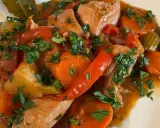 Un saporito spezzatino di pollo con carote, peperoni rossi e prezzemolo tritato, servito in un piatto bianco.