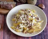 Piatto di pasta alla norcina con salsiccia sbriciolata e ricotta cremosa, un classico della cucina umbra.