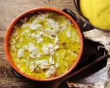 Piatto fumante di baccalà alla vicentina, con polenta gialla e stoccafisso essiccato sullo sfondo.