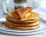 Una pila di dorate crepes senza glutine, una piegata in cima, su un piatto bianco.