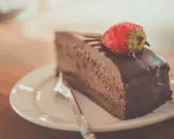 Una fetta di torta al cioccolato, ricoperta di glassa lucida e guarnita con una fragola fresca, pronta per essere gustata.