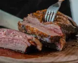 Un succulento arrosto di maiale, tagliato a fette su un tagliere di legno, con una forchetta che affonda nella carne tenera.