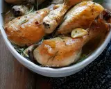 Succulente cosce di pollo al forno, dorate e profumate al rosmarino e aglio, servite in una ciotola bianca.