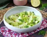 Delicate ribbons of zucchine marinate crude, tossed with fresh mint and pink peppercorns, served in a white bowl.