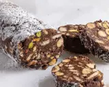 Salame di cioccolato senza uova, ricco di biscotti, nocciole e pistacchi, spolverato di zucchero a velo.