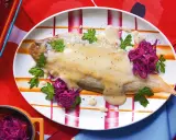 Sogliola alla mugnaia su piatto a righe, guarnita con cavolo rosso e prezzemolo.