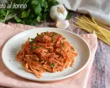 Piatto di spaghetti al sugo con tonno in scatola, guarnito con prezzemolo fresco. Ingredienti per un pasto veloce e gustoso.