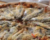 Tortino di alici cotto al forno, con panatura dorata e ingredienti saporiti.