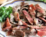 Straccetti di manzo con pancetta e cipolla, guarniti con prezzemolo fresco. Un piatto saporito e invitante.