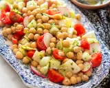 Un'appetitosa insalata di ceci con pomodorini, cetrioli e ravanelli, condita con erbe fresche.
