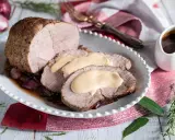 Arrosto di vitello morbido con sughetto benedetta, servito su un piatto bianco con cipolle rosse caramellate e rosmarino.