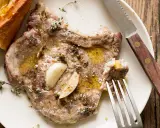 Braciola di maiale succulenta, condita con aglio e erbe aromatiche, servita con pane croccante.