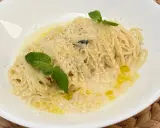 Spaghetti al limone cremosi, cosparsi di parmigiano e guarniti con foglie di menta fresca.