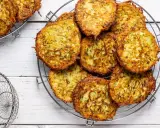 Un mucchio di rosti di zucchine dorati e croccanti su una griglia, pronti per essere gustati.