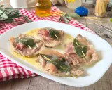 Saltimbocca alla romana su piatto bianco, con prosciutto crudo e salvia, su un tavolo di legno.