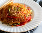 Deliziosi spaghetti di soia con verdure colorate, peperoni rossi, zucchine e carote, guarniti con semi di sesamo.
