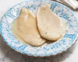 Due scaloppine al vino bianco, tenere e succulente, servite su un piatto decorato con motivi blu.