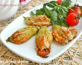 Deliziosi fiori di zucca al forno ripieni, serviti su un piatto bianco con pomodorini e basilico fresco.